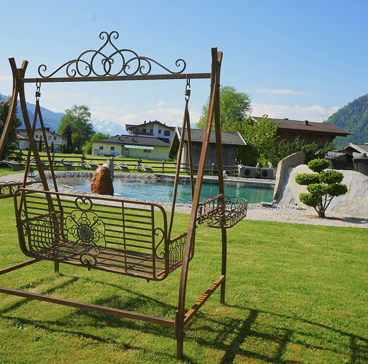 Naturpool mit Vintage-Hollywood-Schaukel im Vordergrund